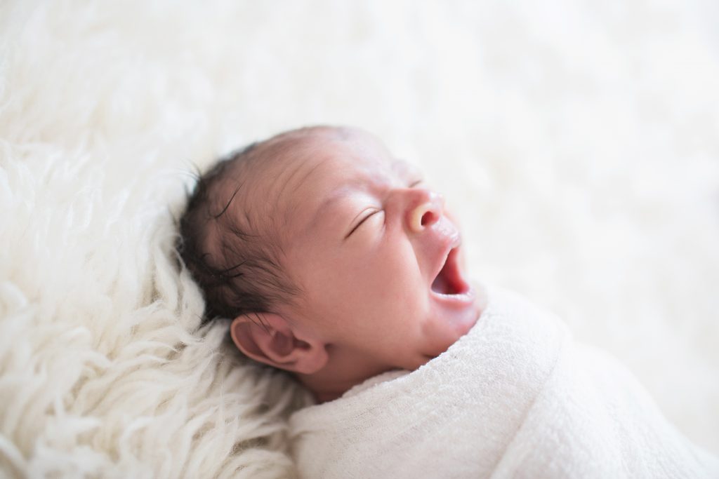 baby in white swaddle yawning.  katie ballantine photographer.  newborn organic photographer.
